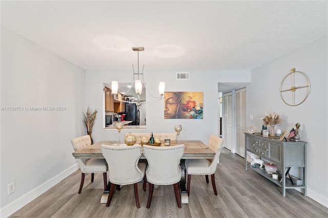 dining room featuring light wood-type flooring and an inviting chandelier