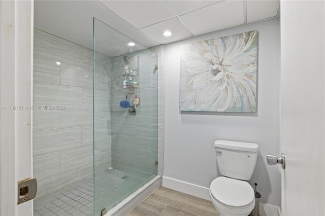 bathroom featuring toilet, wood-type flooring, and tiled shower