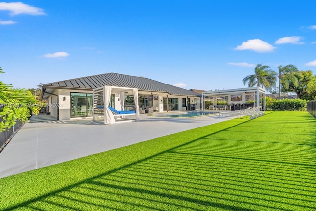 rear view of house with a fenced in pool, a patio area, and a lawn