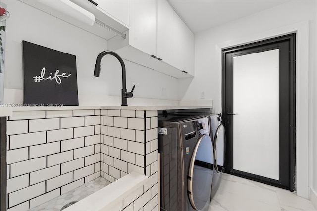 clothes washing area featuring cabinets and washing machine and clothes dryer