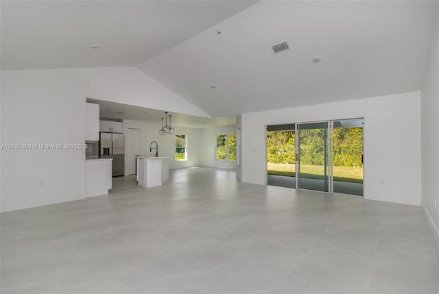 unfurnished living room with visible vents, high vaulted ceiling, baseboards, and a sink