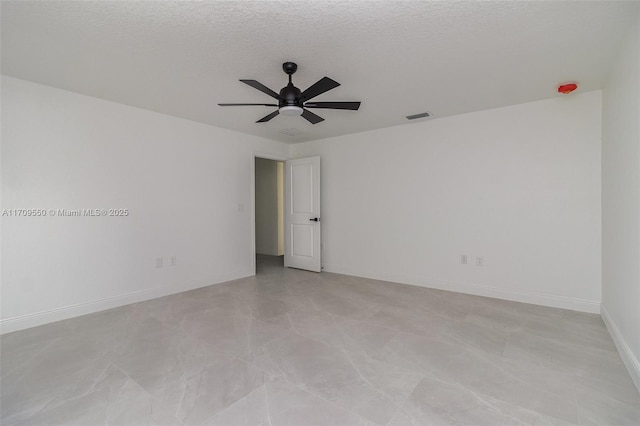 unfurnished room featuring visible vents, baseboards, a textured ceiling, and ceiling fan