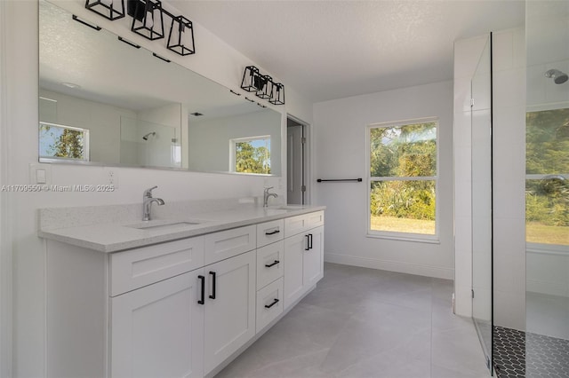 full bath featuring a sink, baseboards, tiled shower, and double vanity