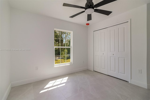 unfurnished bedroom with a closet, light tile patterned floors, ceiling fan, and baseboards