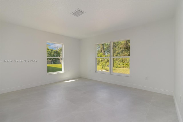 spare room with plenty of natural light, baseboards, and visible vents