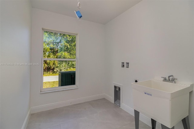 laundry area featuring laundry area, washer hookup, baseboards, and a sink