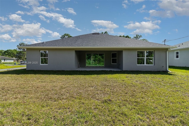 back of house with stucco siding, a patio, a lawn, and roof with shingles