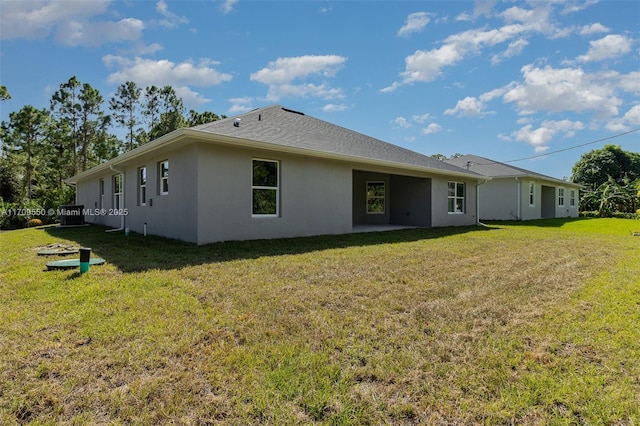 back of property with stucco siding, a patio, a lawn, and roof with shingles