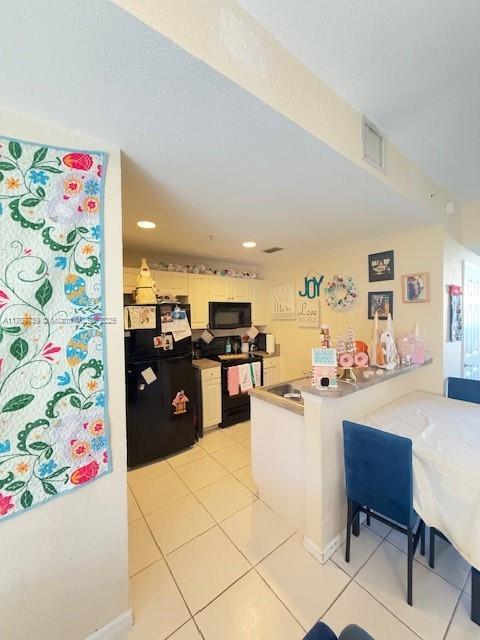 1967 Marsh Harbor Dr Unit 313, Riviera Beach, FL 33404 - kitchen featuring black appliances, a peninsula, light tile patterned flooring, a kitchen breakfast bar, and recessed lighting