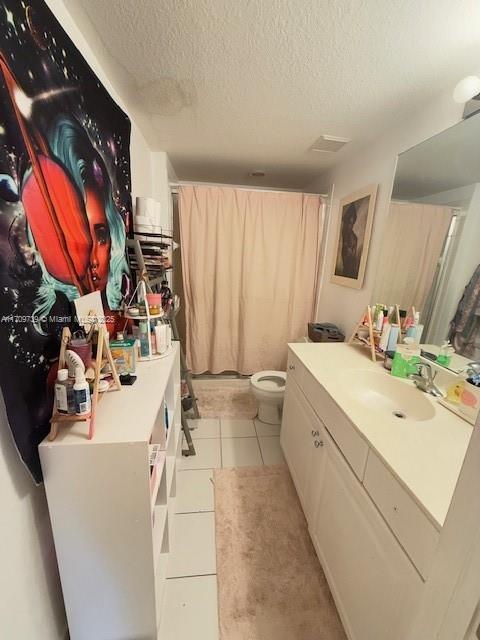 bathroom featuring tile patterned floors, vanity, toilet, and a textured ceiling