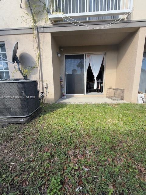 property entrance featuring a yard, a balcony, and cooling unit