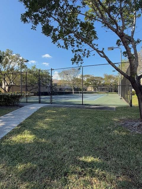 view of home's community featuring a yard and tennis court