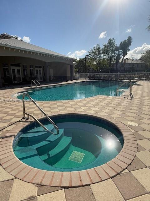 view of swimming pool with a hot tub and a patio area