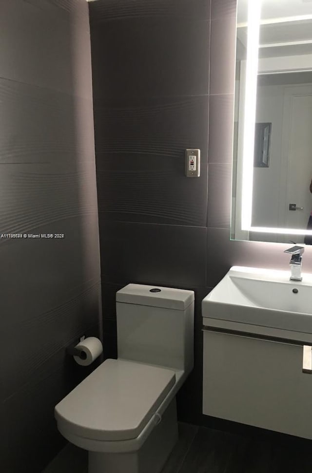 bathroom with vanity, toilet, and tile walls