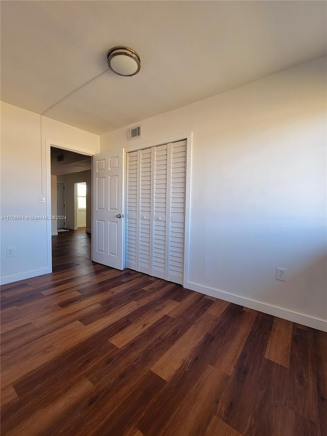 unfurnished bedroom featuring a closet and dark wood-type flooring