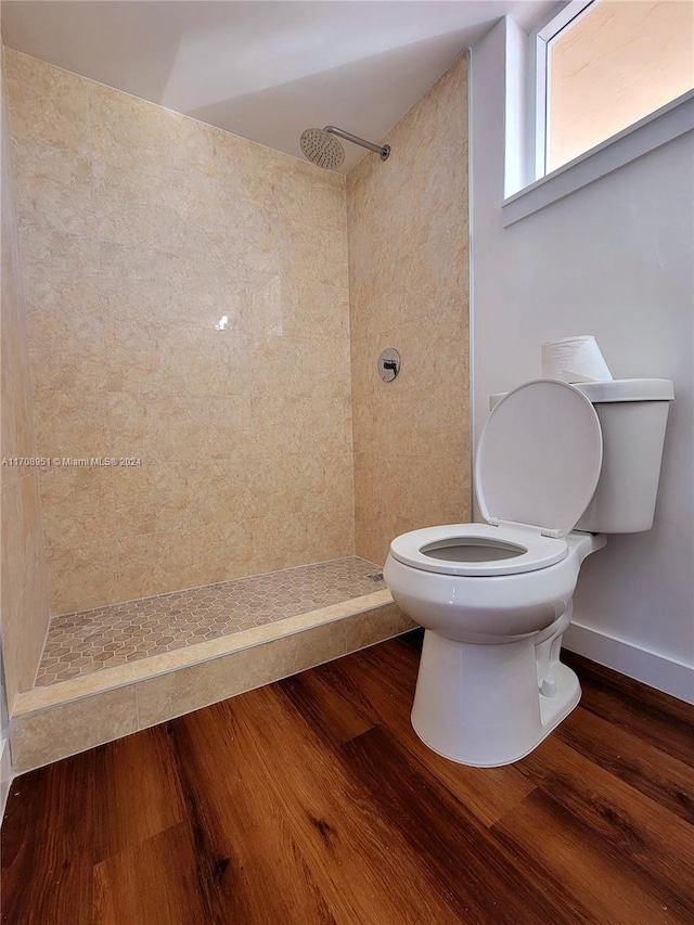 bathroom featuring tiled shower, hardwood / wood-style floors, and toilet