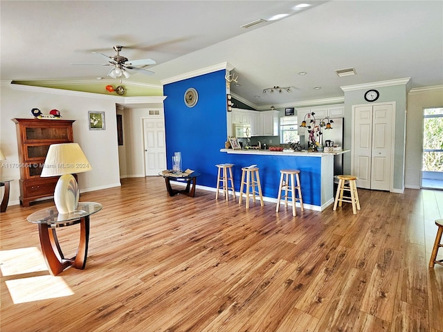 living room featuring light hardwood / wood-style flooring, ceiling fan, and crown molding