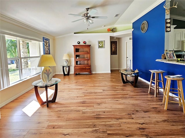 living area featuring light hardwood / wood-style floors, ornamental molding, and vaulted ceiling