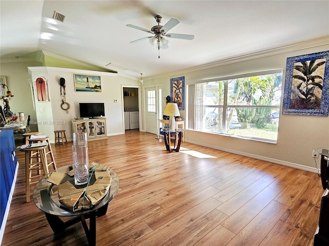 living room with washer and clothes dryer, lofted ceiling, ornamental molding, and light hardwood / wood-style flooring