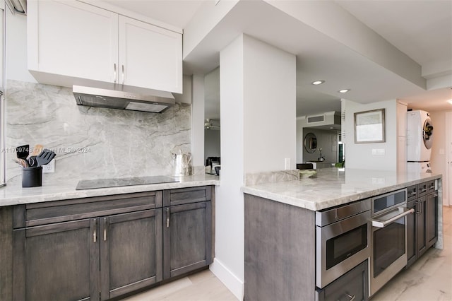 kitchen with decorative backsplash, light stone countertops, appliances with stainless steel finishes, dark brown cabinets, and white cabinetry