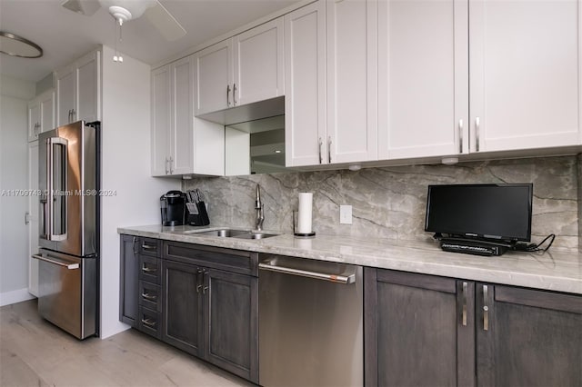 kitchen with light stone countertops, appliances with stainless steel finishes, light wood-type flooring, sink, and white cabinetry