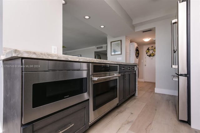 kitchen featuring light stone counters, stainless steel appliances, and light wood-type flooring