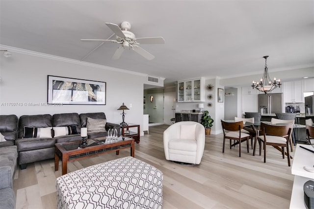 living room featuring ceiling fan with notable chandelier, light wood-type flooring, and ornamental molding