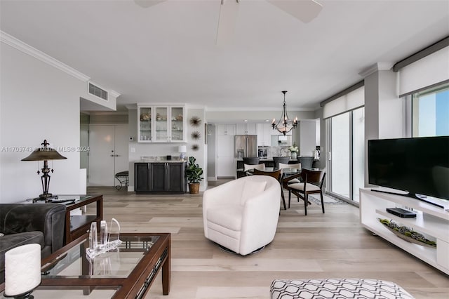 living room featuring crown molding, light hardwood / wood-style flooring, and an inviting chandelier