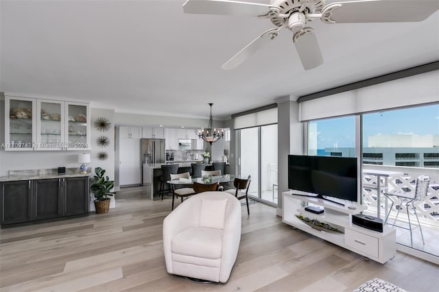 living room featuring crown molding, light hardwood / wood-style floors, and ceiling fan with notable chandelier