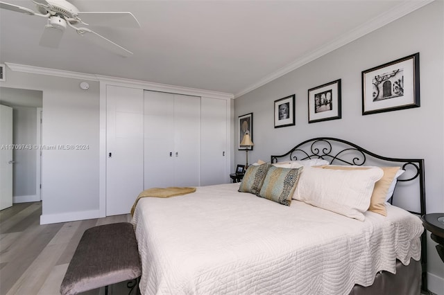 bedroom featuring ceiling fan, light hardwood / wood-style floors, ornamental molding, and a closet