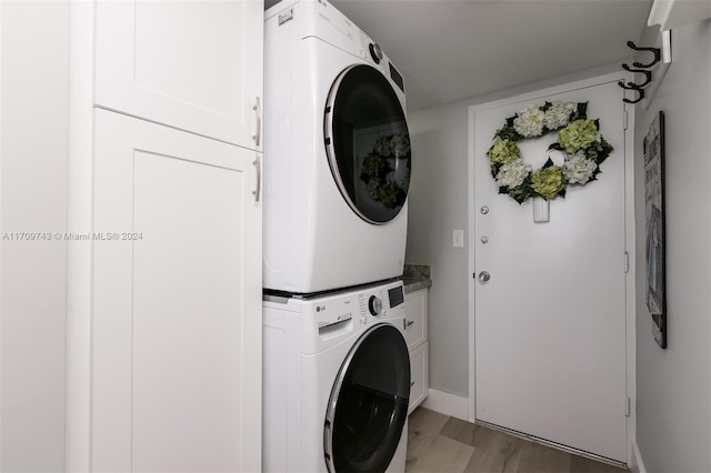 clothes washing area with cabinets, stacked washer / drying machine, and light wood-type flooring