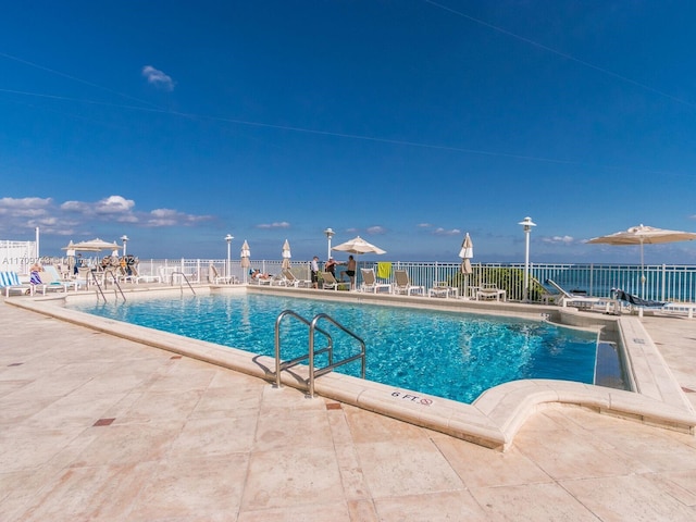 view of pool with a patio area and a water view