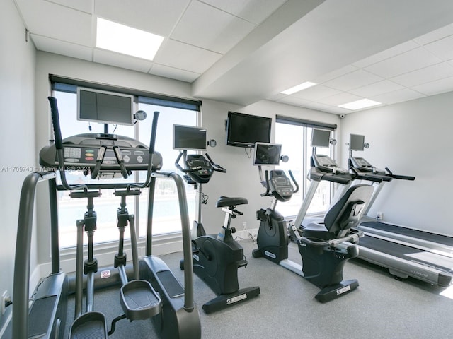 gym with a drop ceiling and a healthy amount of sunlight