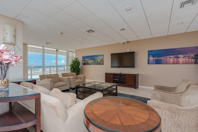 living room with floor to ceiling windows and a drop ceiling