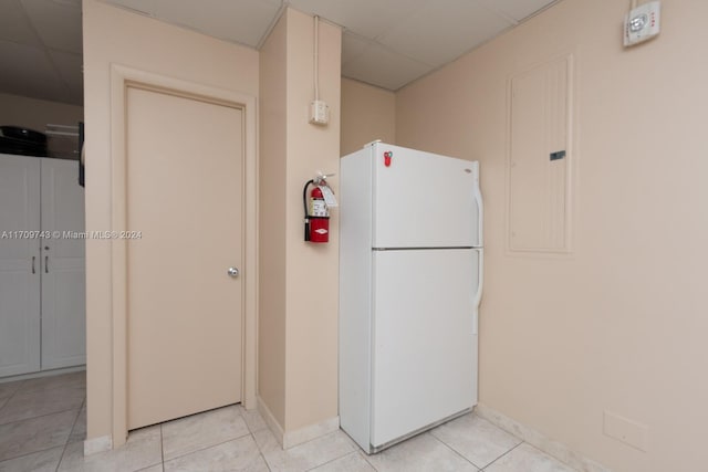 kitchen with light tile patterned floors, white refrigerator, and a drop ceiling