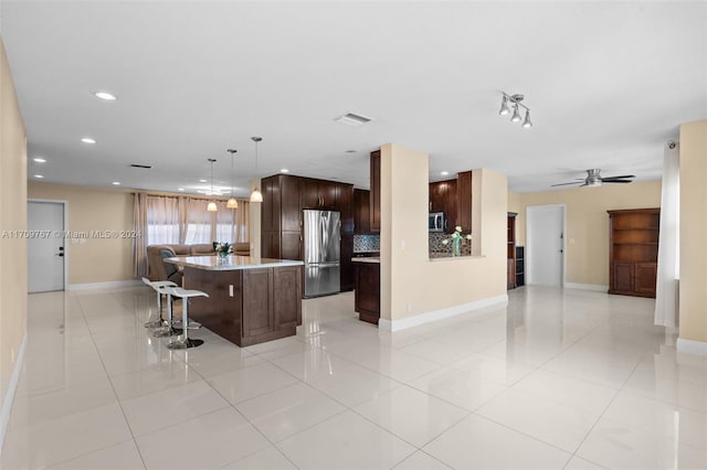 kitchen featuring stainless steel appliances, light tile patterned floors, decorative light fixtures, a center island, and a breakfast bar area