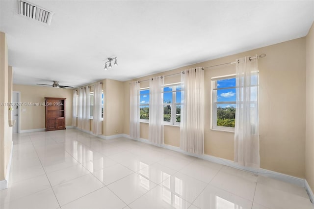 spare room featuring ceiling fan, light tile patterned floors, and a wealth of natural light