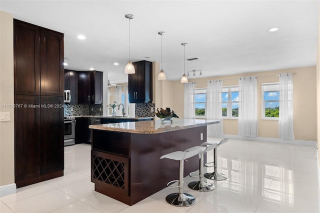 kitchen featuring stainless steel electric stove, backsplash, hanging light fixtures, and a kitchen breakfast bar