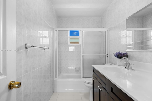 full bathroom with enclosed tub / shower combo, tile patterned floors, toilet, vanity, and tile walls