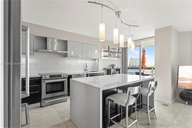 kitchen featuring appliances with stainless steel finishes, a breakfast bar, wall chimney range hood, white cabinets, and a kitchen island