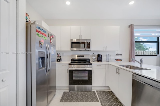 kitchen with light tile patterned flooring, appliances with stainless steel finishes, white cabinetry, and sink