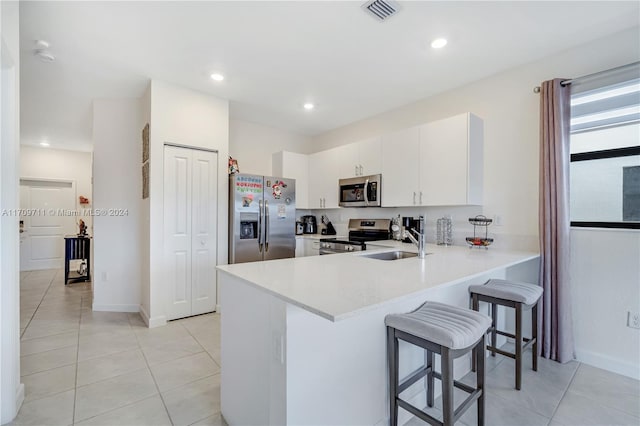 kitchen with sink, kitchen peninsula, a kitchen bar, white cabinetry, and stainless steel appliances