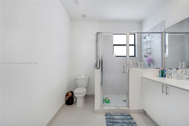 bathroom featuring toilet, vanity, tile patterned floors, and an enclosed shower