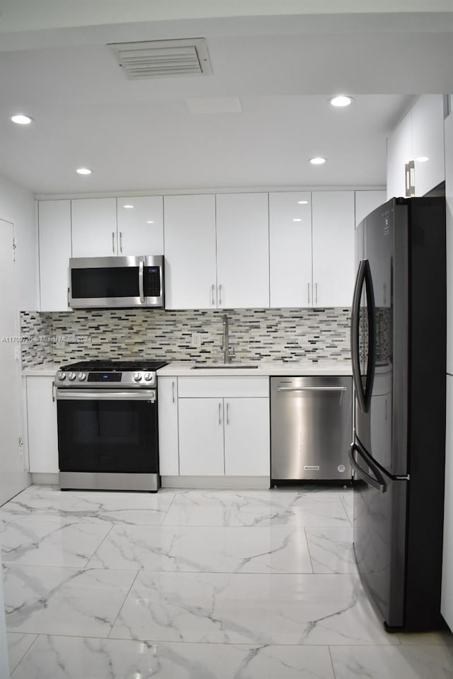 kitchen with white cabinets, backsplash, sink, and stainless steel appliances