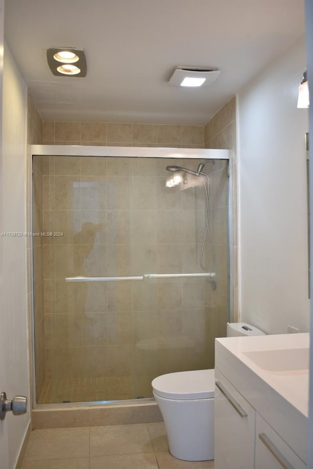 bathroom featuring tile patterned flooring, vanity, a shower with door, and toilet