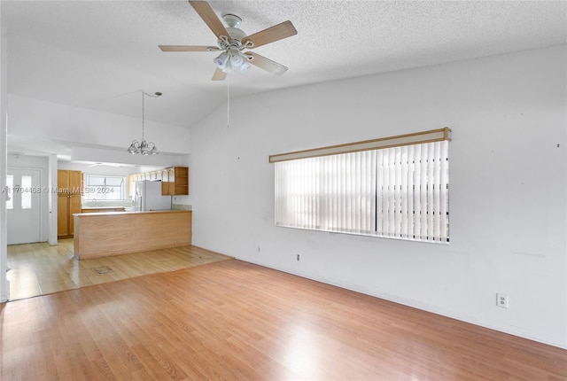 unfurnished living room featuring a textured ceiling, ceiling fan, light hardwood / wood-style floors, and lofted ceiling