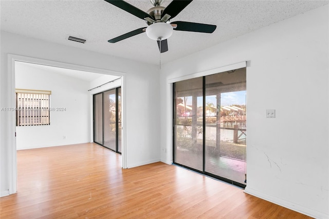 spare room with a textured ceiling, light hardwood / wood-style floors, and plenty of natural light