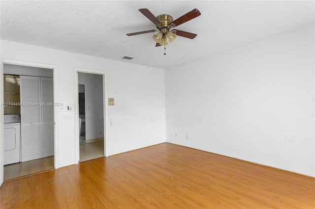 unfurnished bedroom featuring washer / clothes dryer, ceiling fan, light hardwood / wood-style flooring, and a textured ceiling