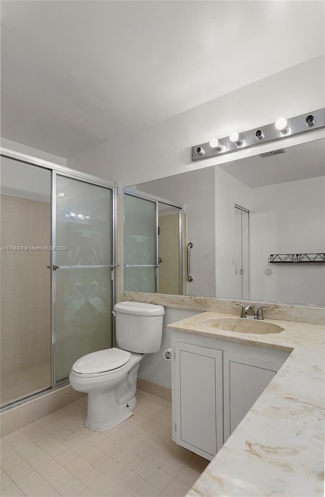 bathroom with tile patterned flooring, vanity, toilet, and an enclosed shower