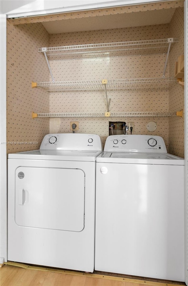 laundry area with washer and clothes dryer and light wood-type flooring